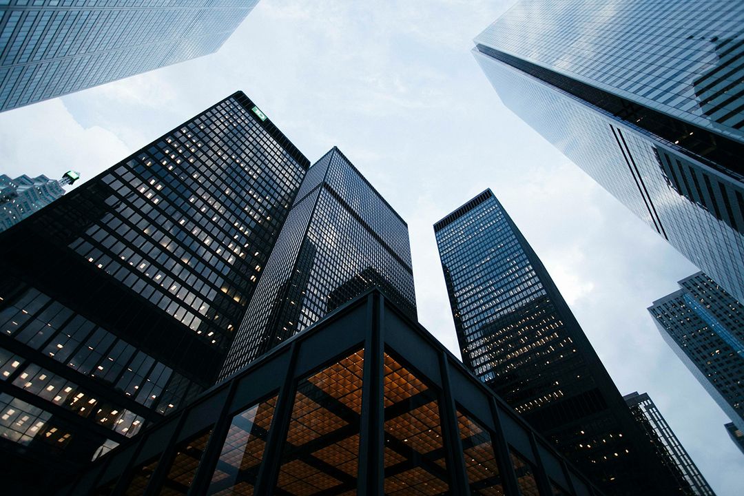 Corporate towers photographed from street level against an overcast sky
