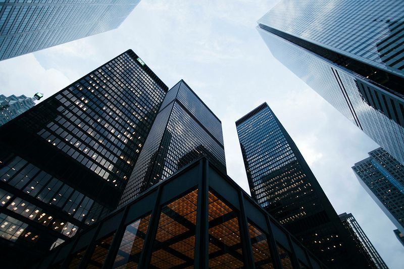 Corporate towers photographed from street level against an overcast sky